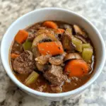 A hearty bowl of keto beef stew with mushrooms, carrots, celery, and tender beef in a rich broth – a comforting low carb, gluten free meal made in the slow cooker.